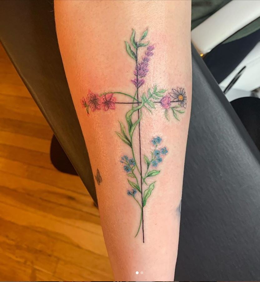 Screenshot of cross wrapped in flowers on someone's inner forearm